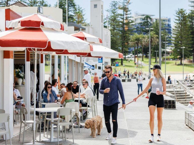 People dining and couple walking with dog in front of Bobby's Cronulla