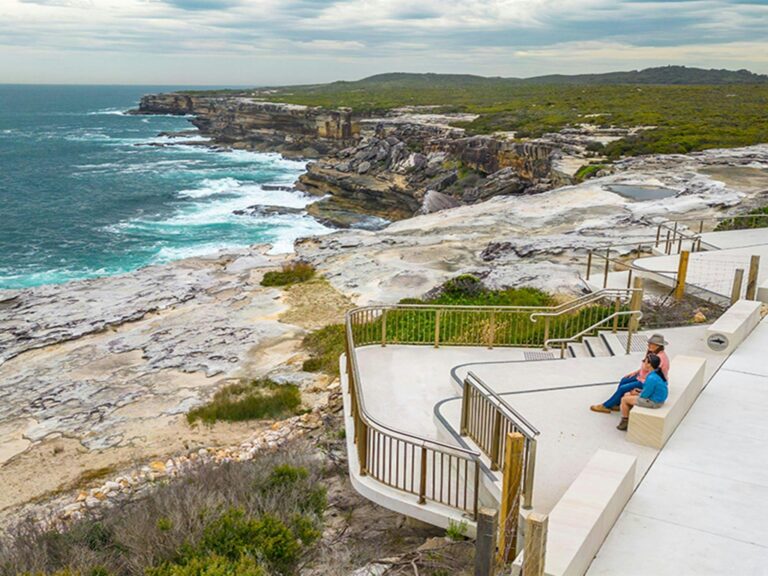 People looking out over the ocean from the whale watching platform at Cape Solander. Photo: John